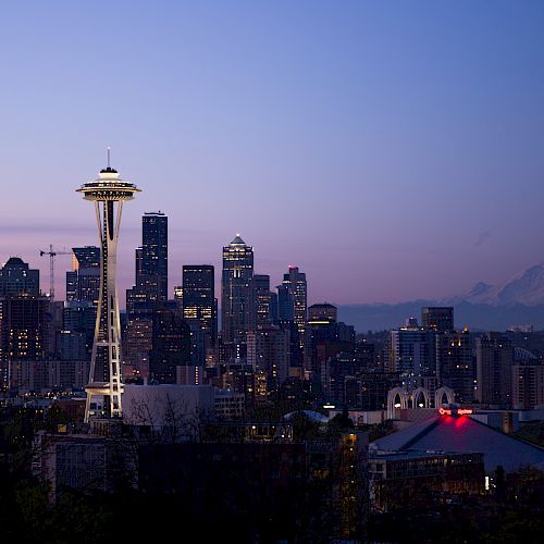This image features the Seattle skyline at dusk, showcasing the Space Needle and city buildings with Mount Rainier in the background.